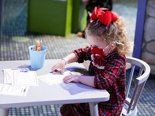 Little girl with a mask working on a color sheet.