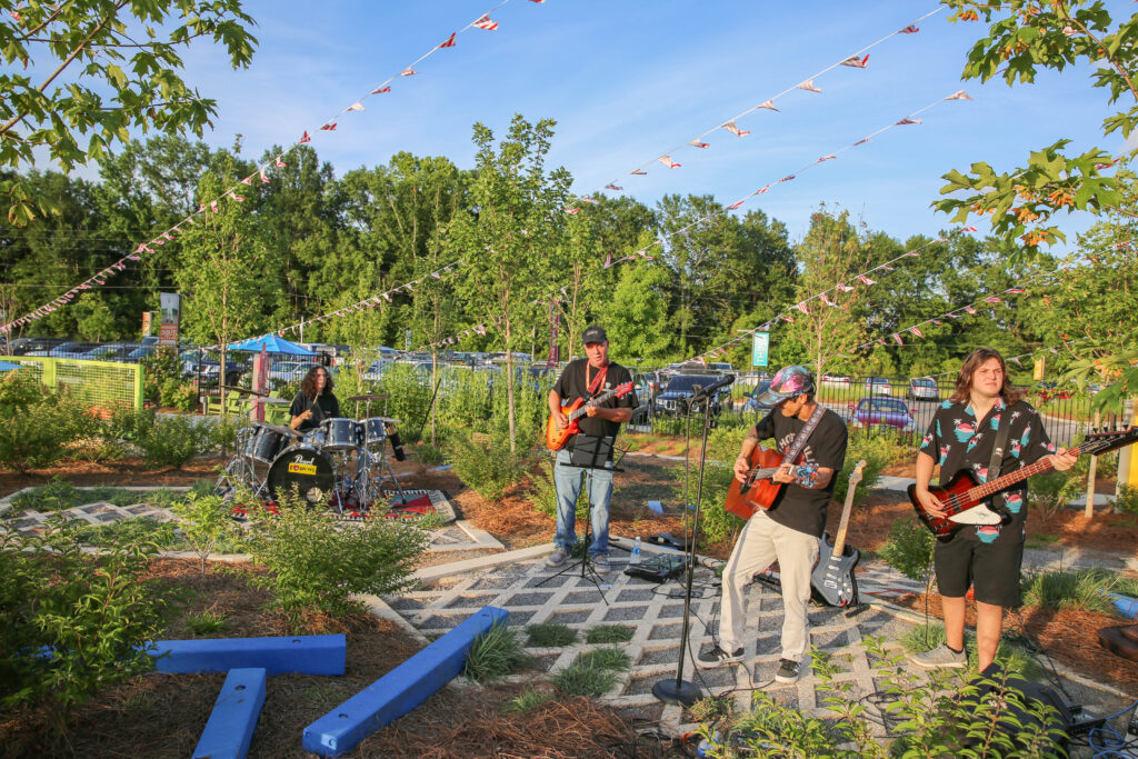 Guitar players and a drummer playing music outside