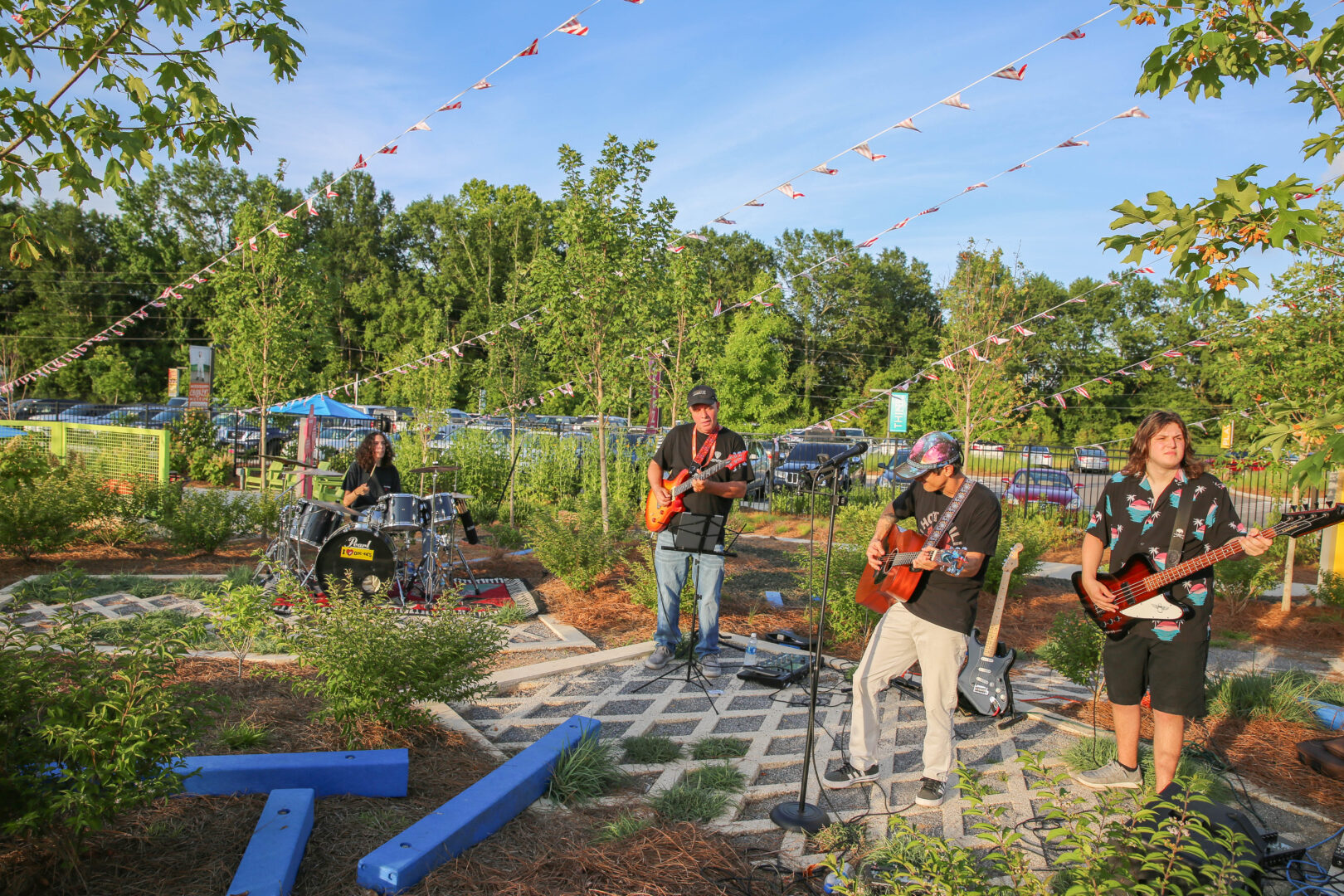 Guitar players and a drummer playing music outside